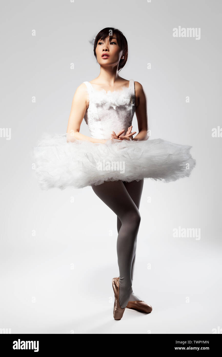An asian ballerina posing in a studio setting wearing a white tutu and black bodysuit Stock Photo