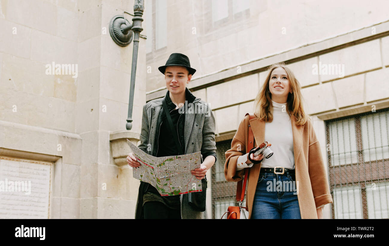 Two stylish friend standing at the street and look for something using ...