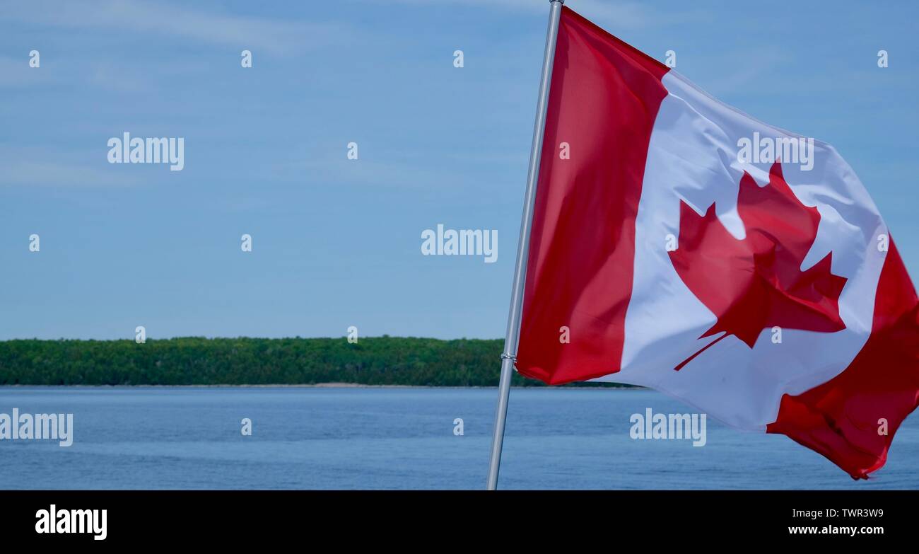 Canadian flag is waving in the wind on a boat cruise Stock Photo
