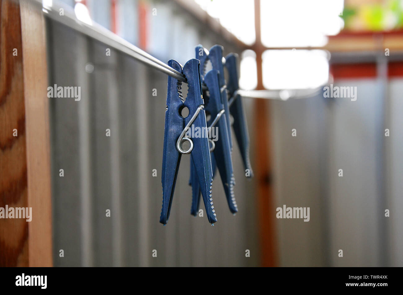 Several blue plastic clothes pins on the cord on the balcony, selective focus Stock Photo