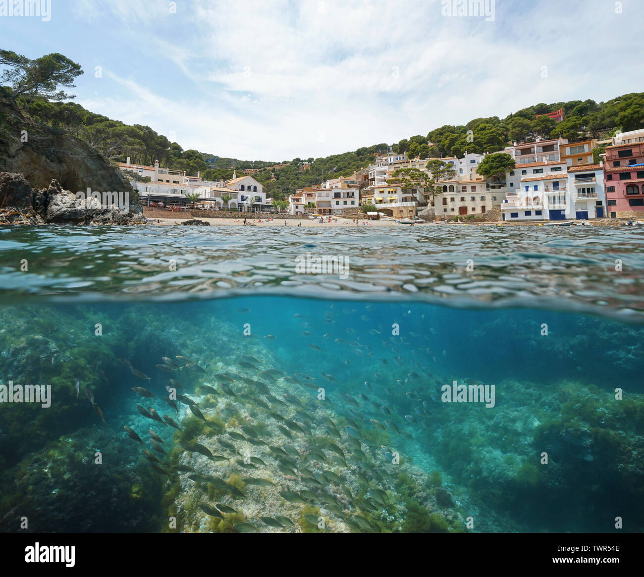 Spain coastal village with beach and fish underwater, Mediterranean sea, Sa Tuna cove, Begur, Costa Brava, Catalonia, split view over and under water Stock Photo