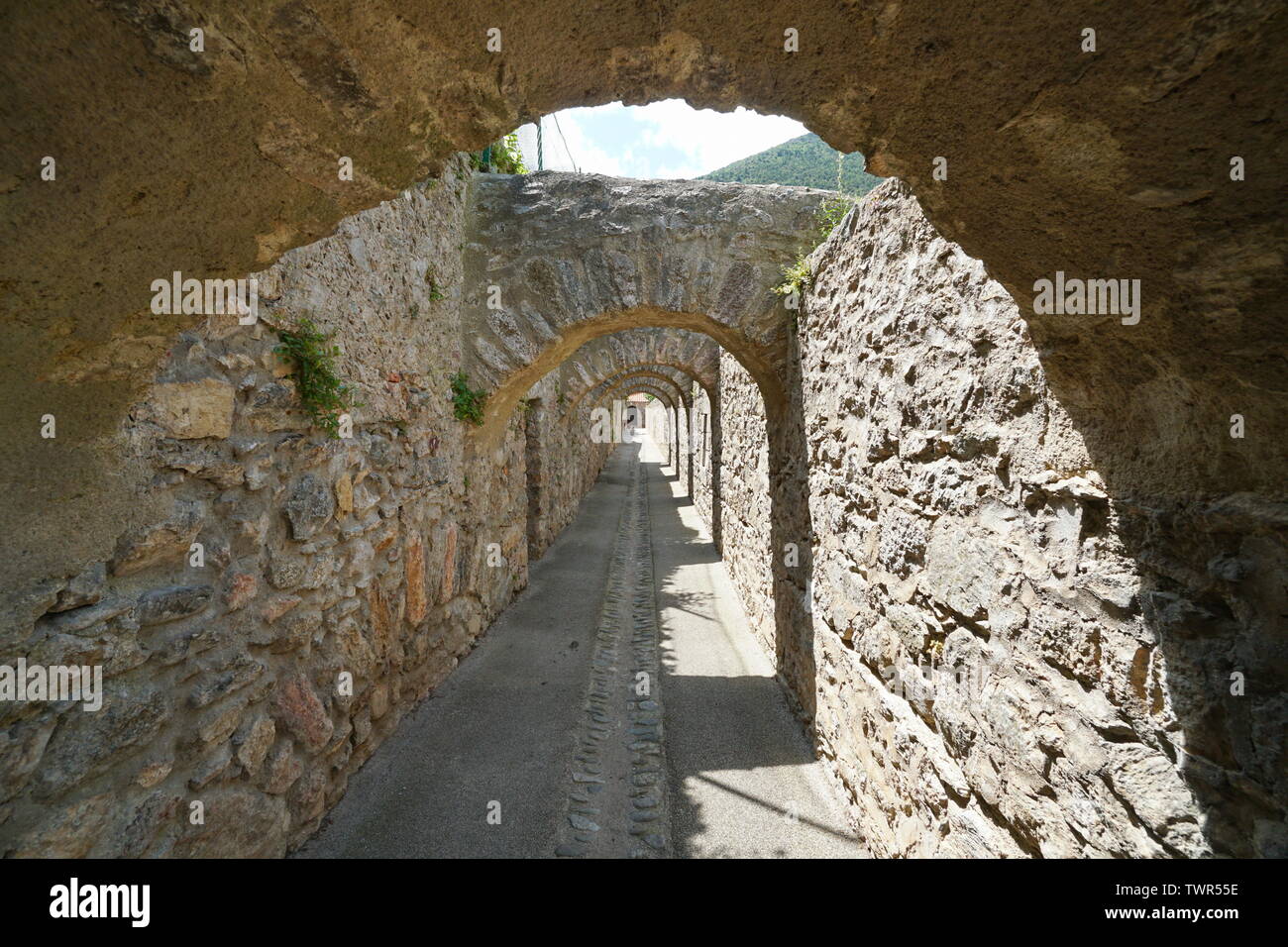 Passage under stone arches inside the fortified village of Villefranche de Conflent, Pyrenees Orientales, Occitanie, France Stock Photo