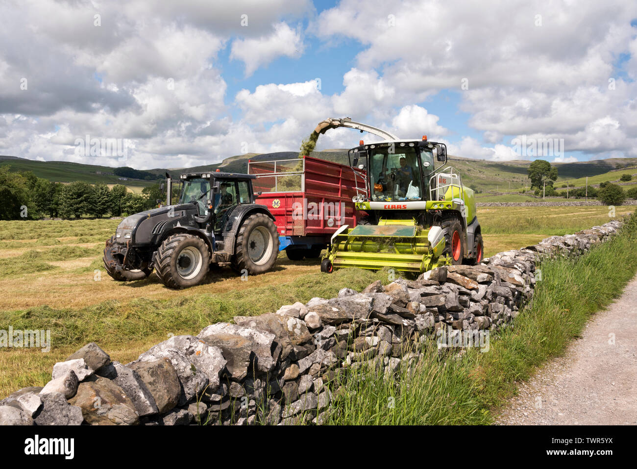 Farmers take advantage of a day of dry Summer weather to cut hay meadows and collect the grass for silage-making, Austwick, North Yorkshire. Stock Photo