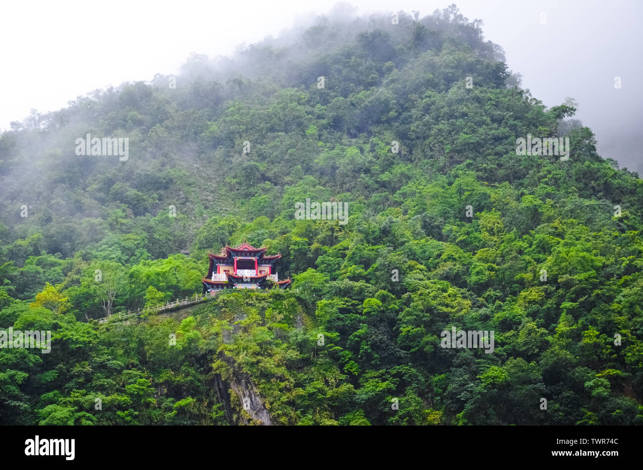 Magnificent Chinese temple on a steep rock surrounded by green tropical ...