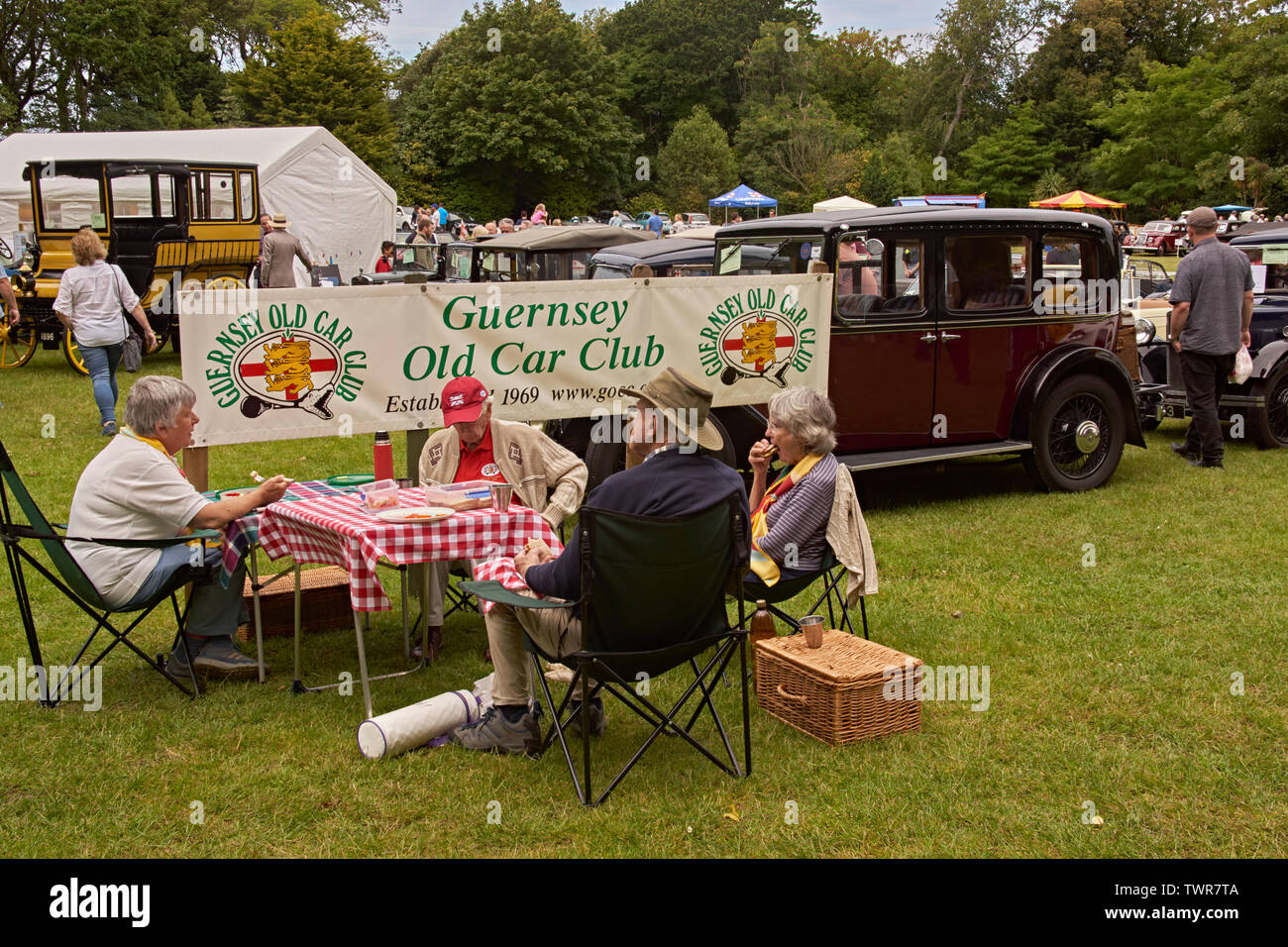 Vintage car enthusiasts taking refreshments alongside their vehicles at