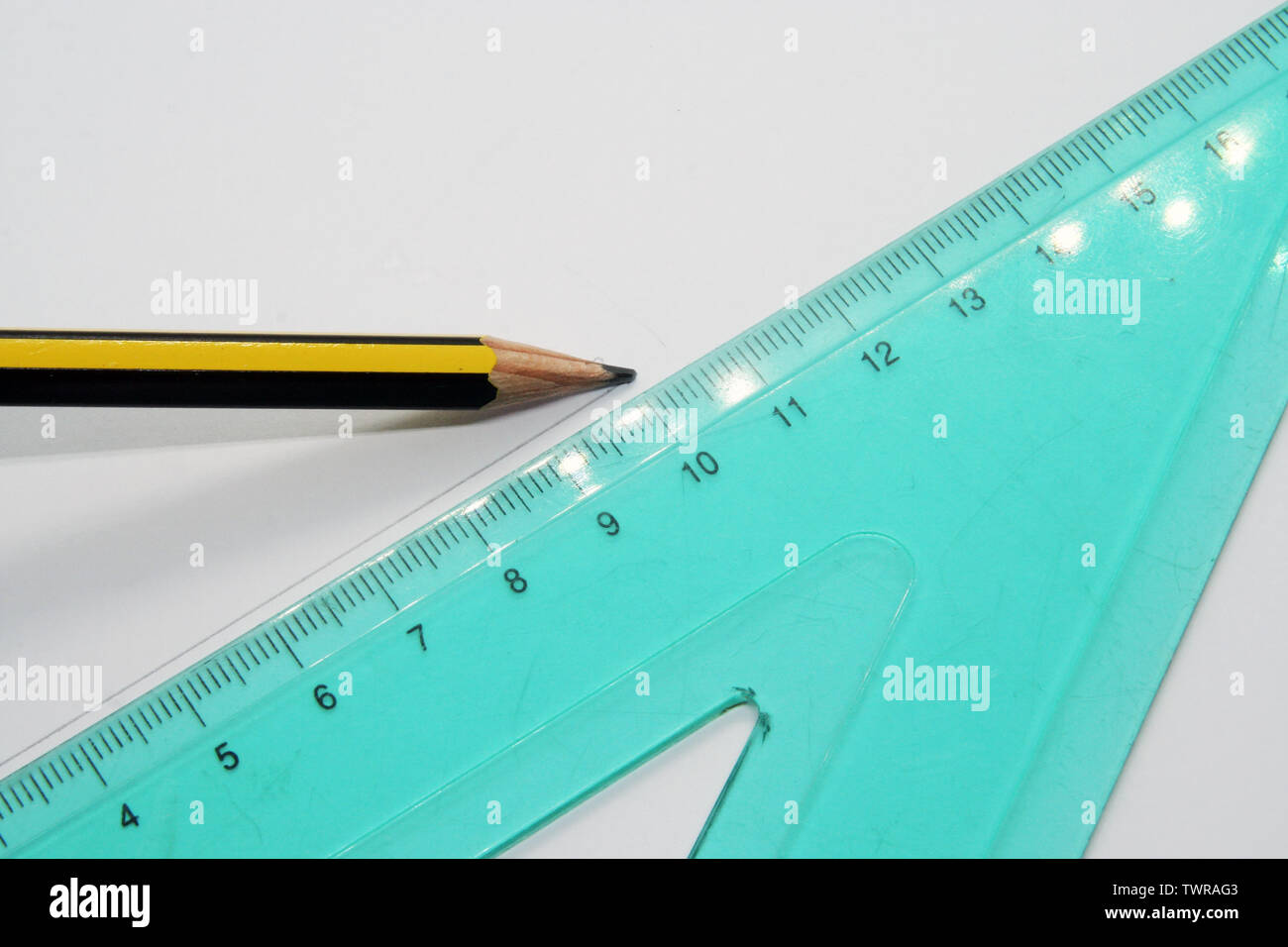 Old used triangle ruler and a pencil. Ruler and pencil. Stock Photo