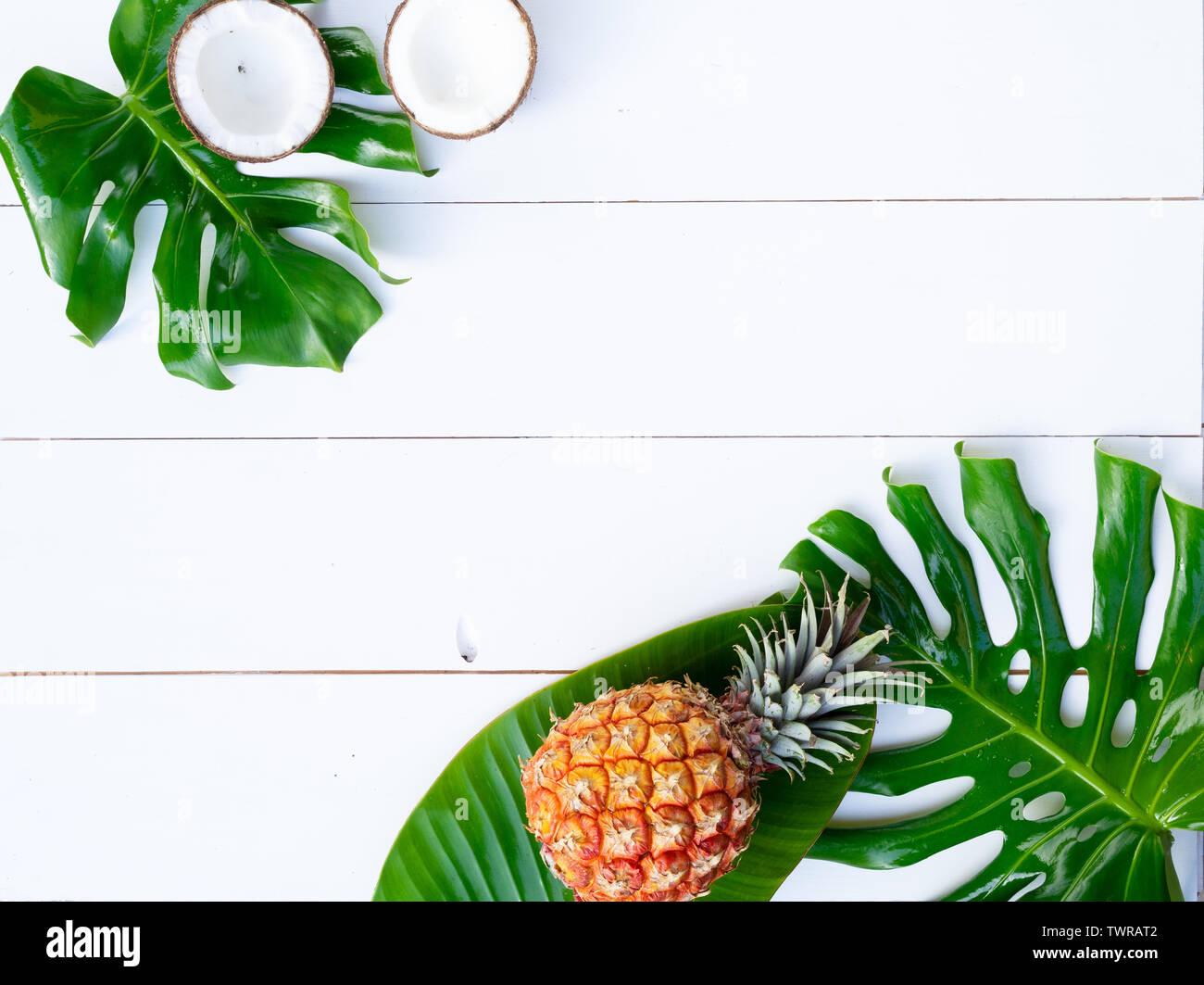 Summer flat lay scenery with tropical green leaves and friuts on white ...