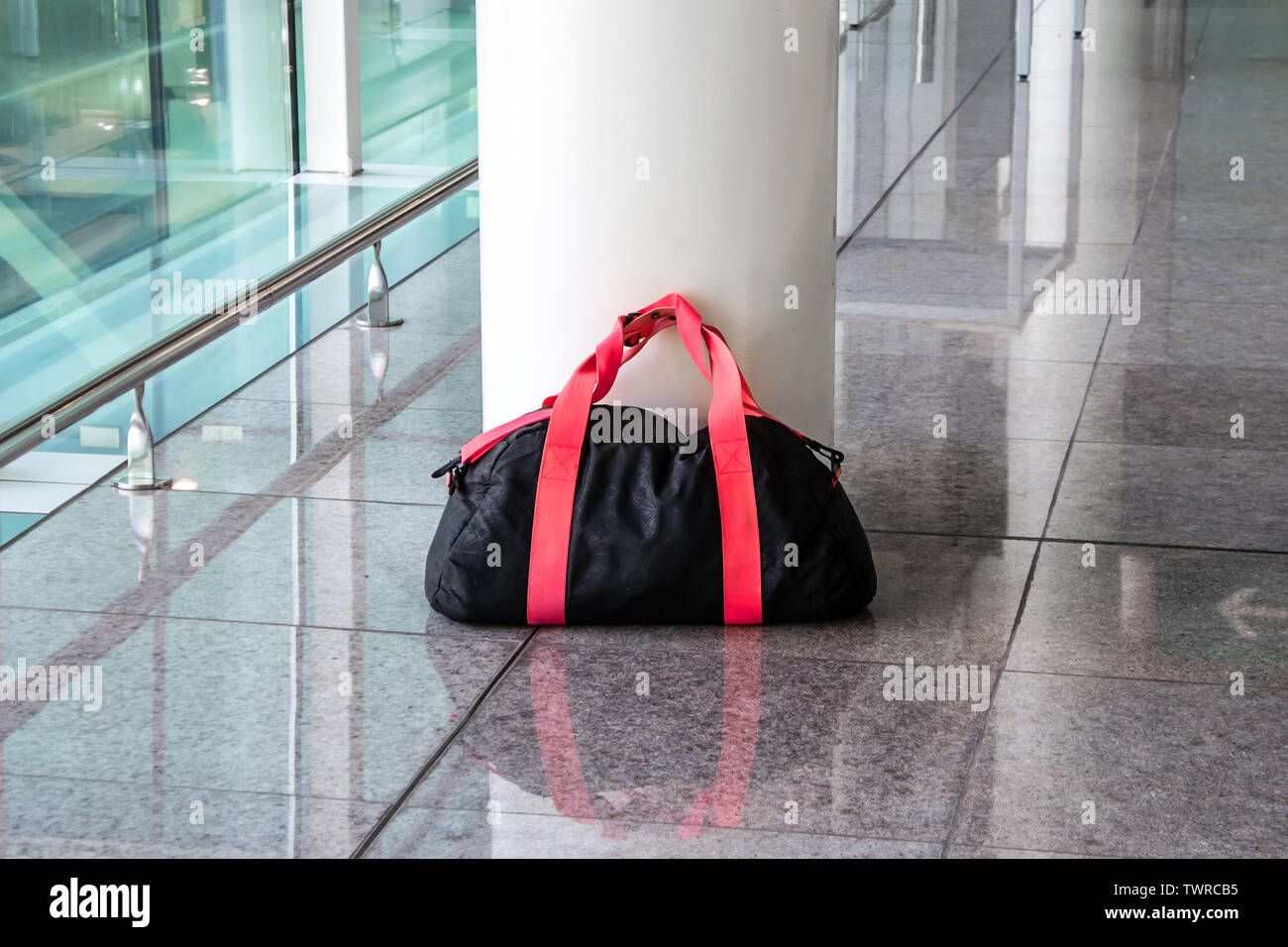 Suspicious black and red bag left unattended in an empty hall. Concept of terrorism and public safety. Stock Photo