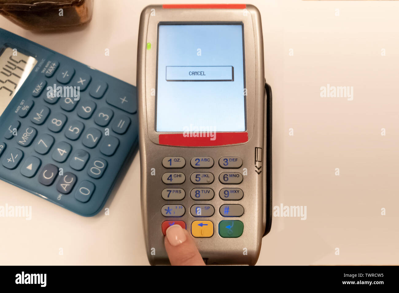 Woman pushing red button on TVP electronic terminal to cancel the  operation. White background and blue calculator to the left Stock Photo -  Alamy