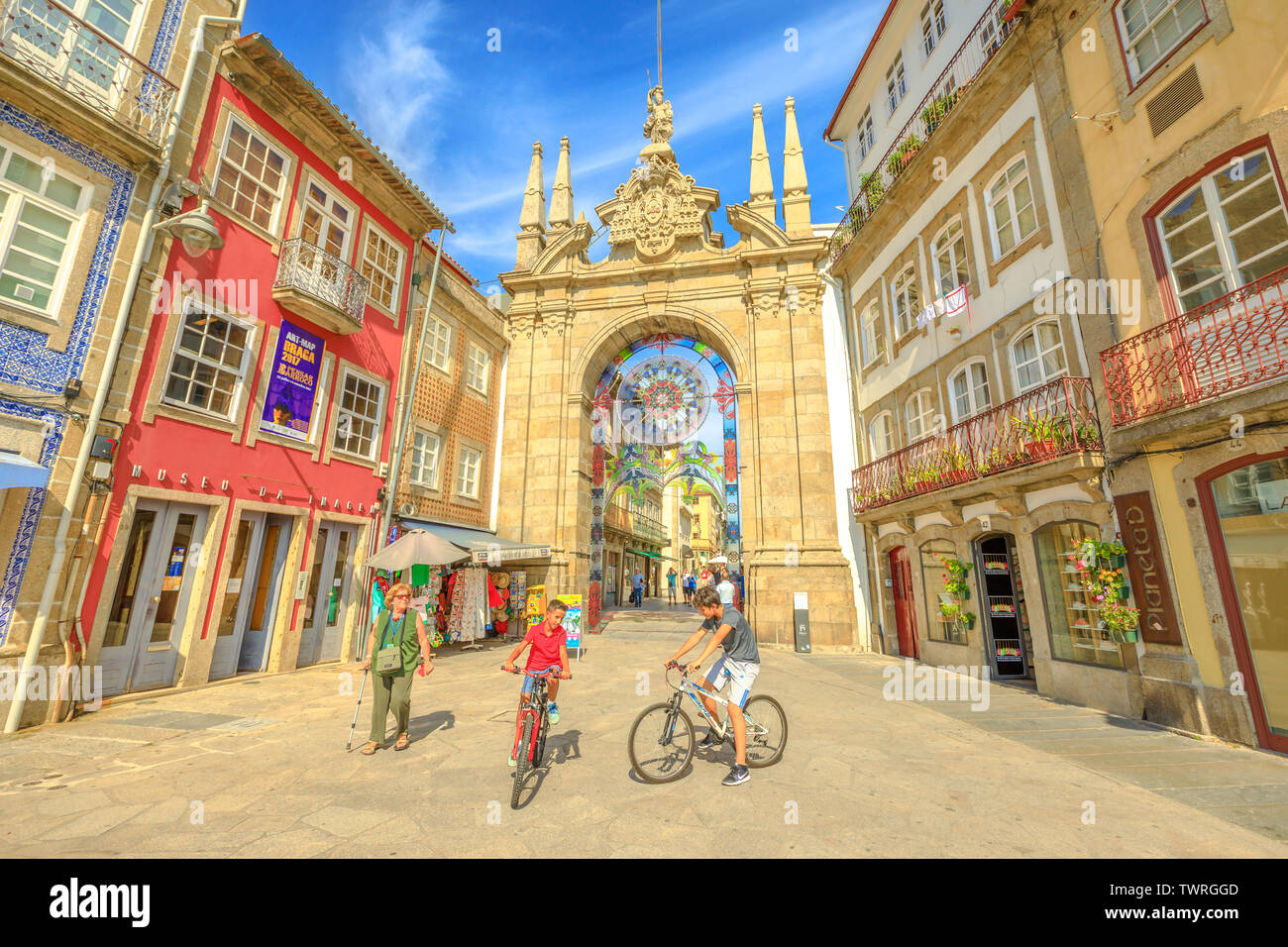 Braga, Portugal - August 12, 2017: children cycling in front of popular Arco da Porta Nova. Arch of New Gate in Baroque style is part of Braga city Stock Photo