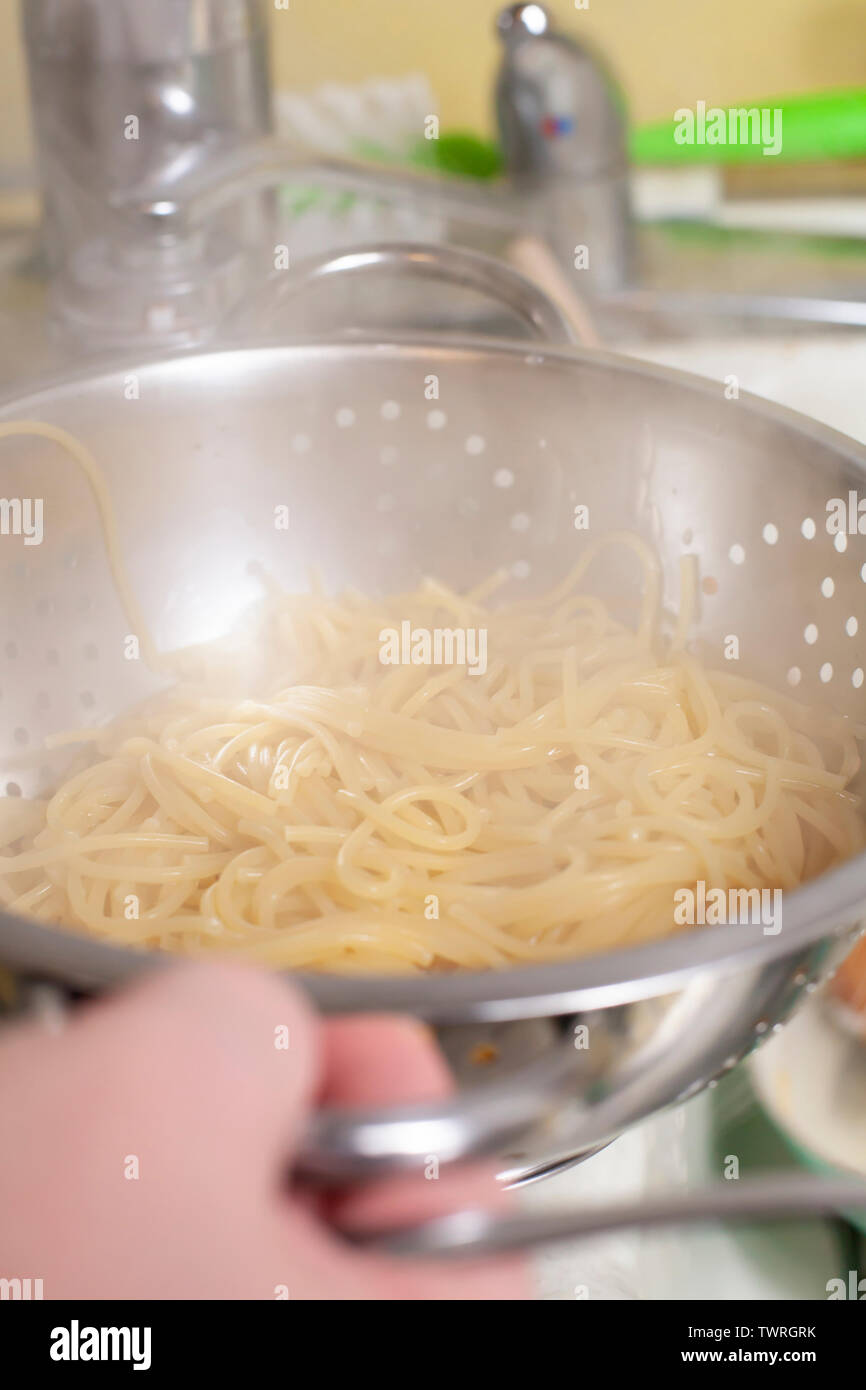 Draining hot, cooked spaghetti noodles in a colander Stock Photo Alamy