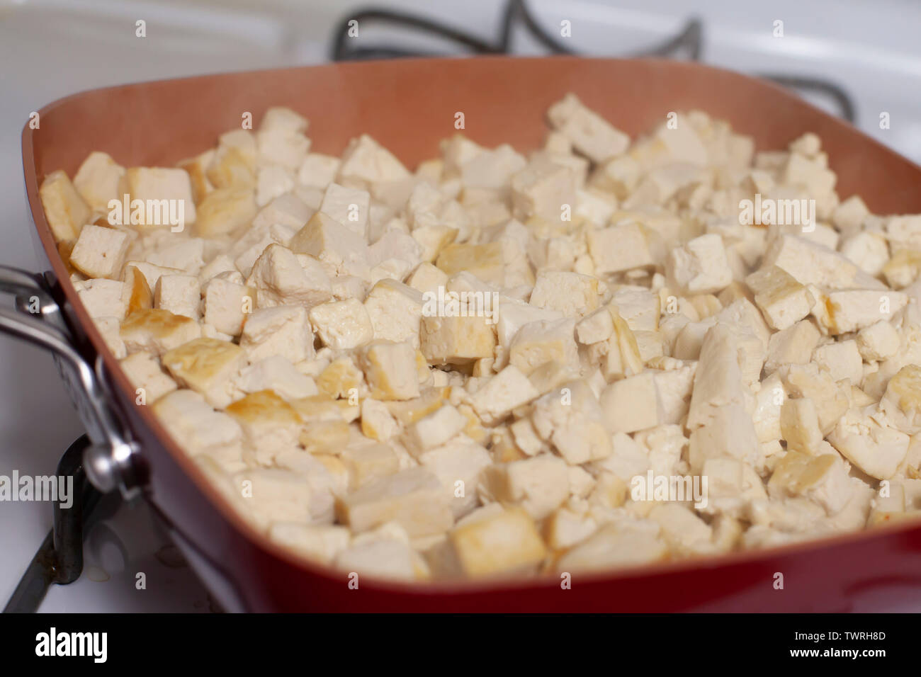 Cubbed tofu browning in a clay frying pan Stock Photo - Alamy