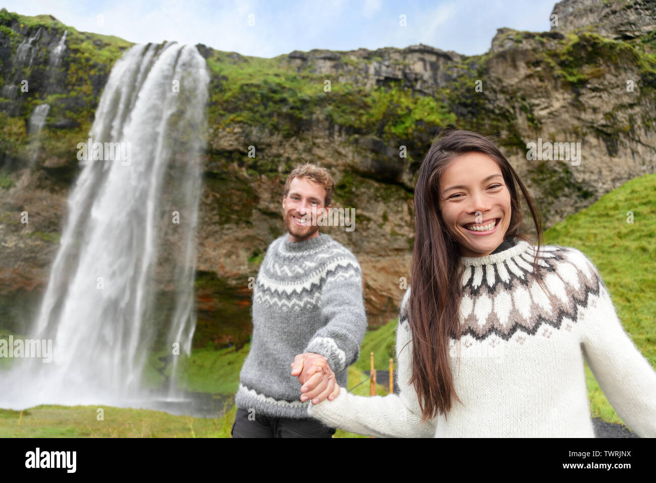 Iceland couple wearing Icelandic sweaters by Seljalandsfoss waterfall on  Ring Road in beautiful nature landscape on Iceland. Woman and man model in  typical Icelandic sweater. Multiracial couple Stock Photo - Alamy