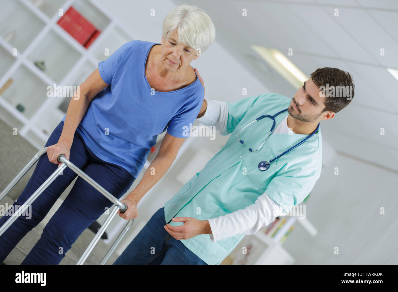 nurse helping senior woman use a walking frame Stock Photo Alamy