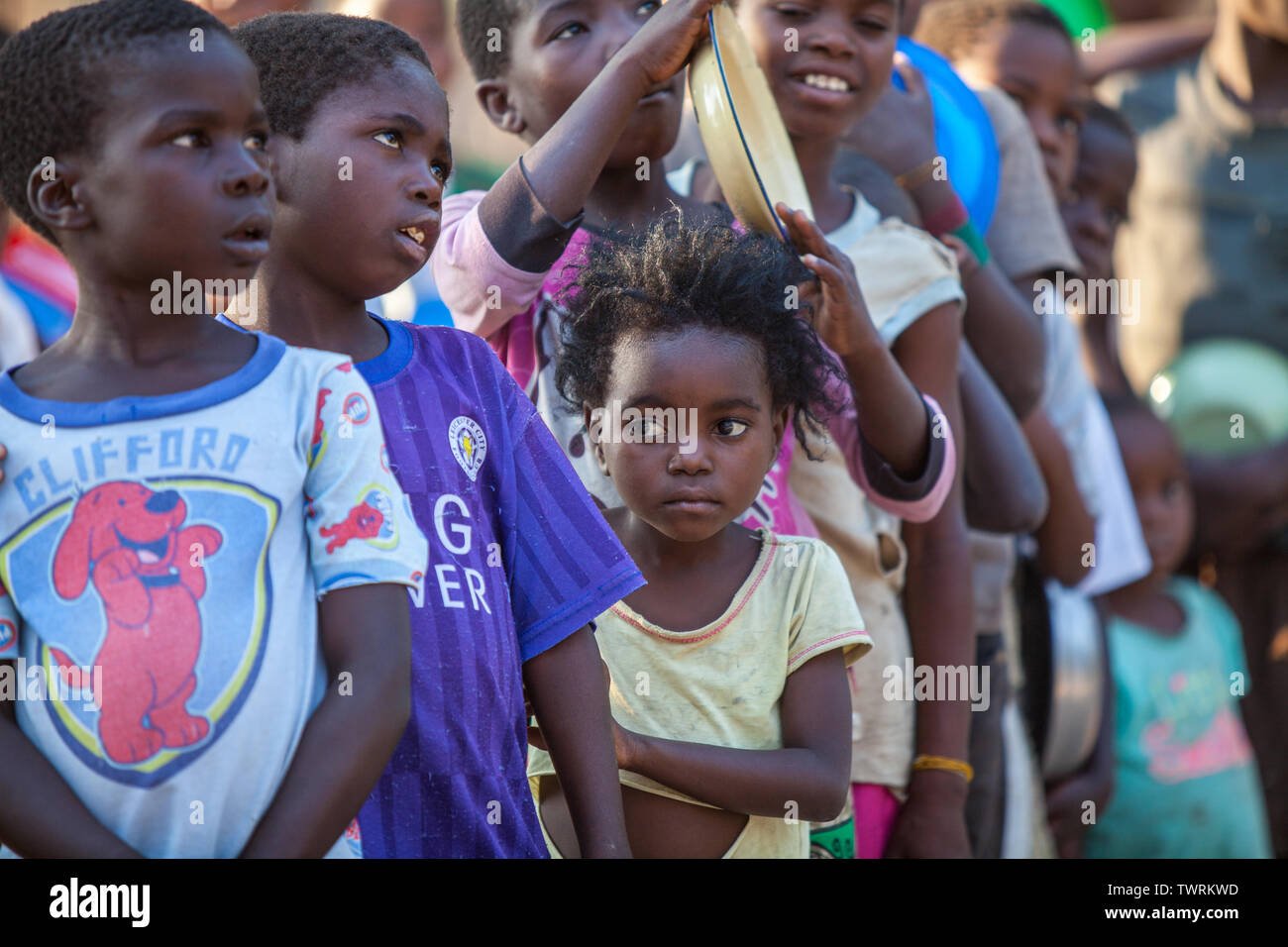 A hungry child waits in line to get food on a hot day Stock Photo