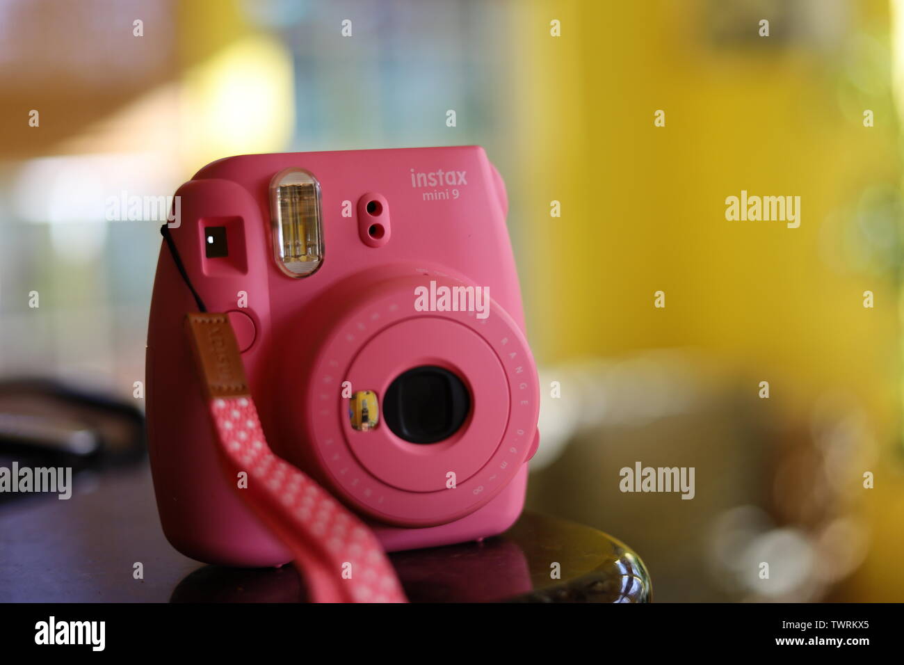 A Pink polaroid camera in a sunlit room with yellow walls Stock Photo -  Alamy