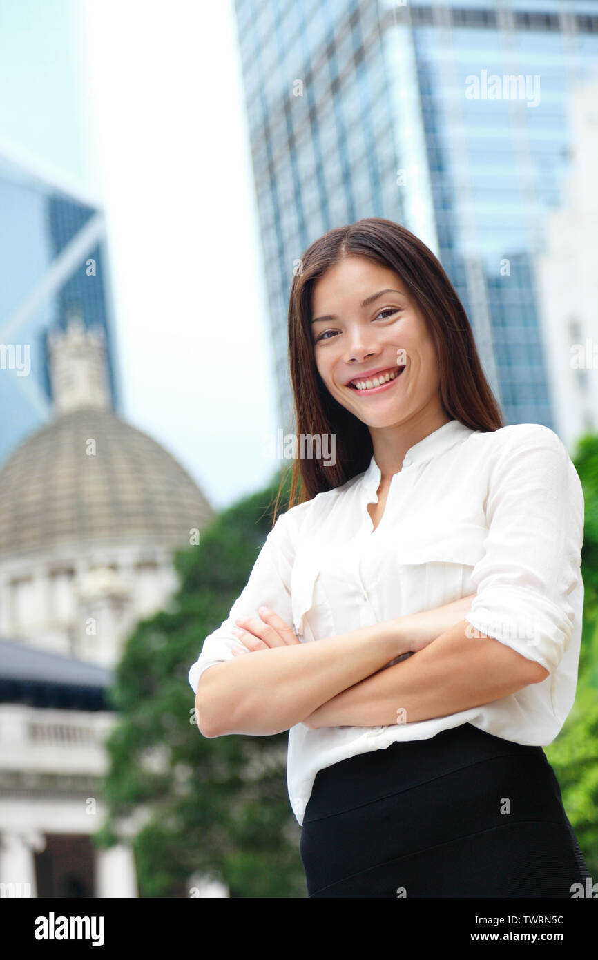 Business woman smiling portrait in Hong Kong. Businesswoman standing happy and successful in suit cross-armed. Young multiracial Chinese Asian / Caucasian female professional in central Hong Kong. Stock Photo