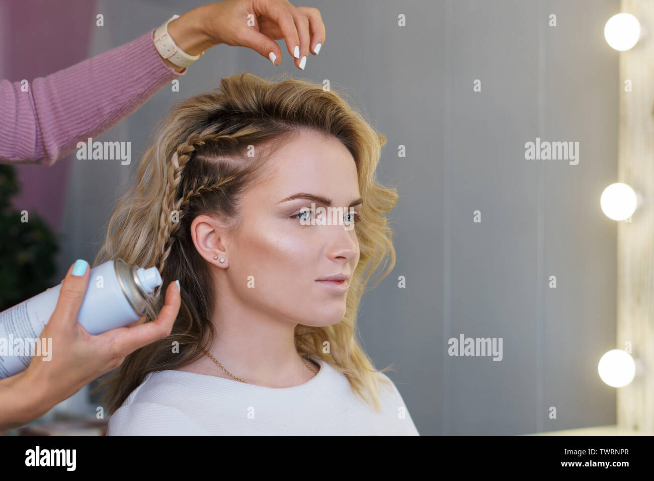 Hairdresser weaving plaits in beauty salon. Hairdressing services. Сreating  hairstyle. Hair styling process. Hair stylist uses spray-shaped hairspray  Stock Photo - Alamy