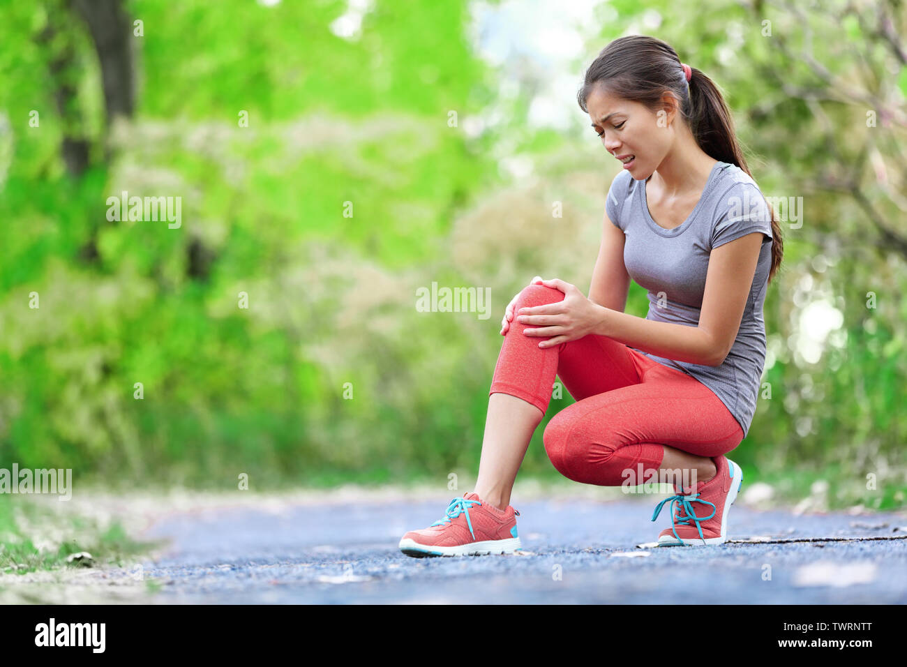 Knee Injury - sports running knee injuries on woman in pain. Female runner with pain from sprain knee. Close up of legs, muscle and knee outdoors. Stock Photo