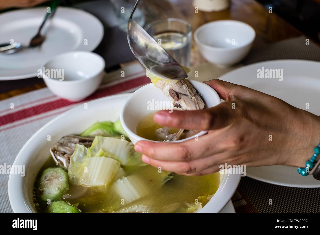 Woman's hand and scooping slice of Pompano fish soup into a small bowl. Pompano fish or Jack also known as Pampano for Filipinos or Trachinotus blochi Stock Photo