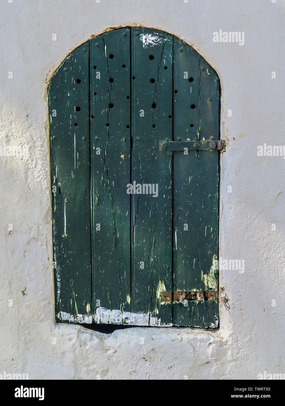 White wash, green door, flaky paint, little door, knubby hole, secret den, storage, latch, small, entrance, vent holes, wooden, planks. Stock Photo