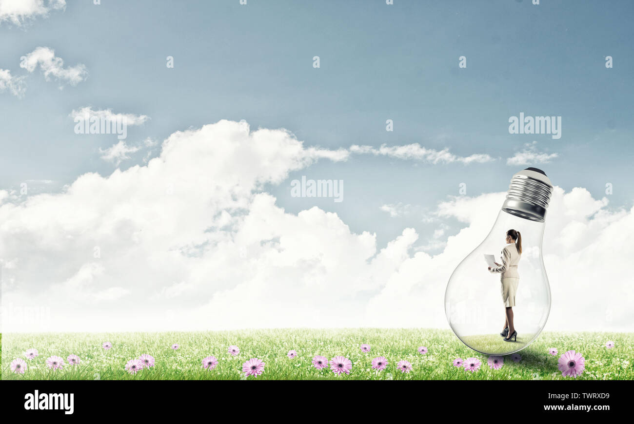 Businesswoman inside glass light bulb outdoors looking away Stock Photo