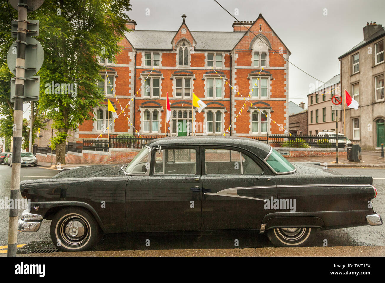 Cork City, Cork, Ireland. 23rd June, 2019. On a wet morning with a status yellow rain warning in place, a 1956 Ford Customline car is parked outside the North Cathedral where bunting has been erected to celebrate the annual Corpus Christi procession that will take place later in the day through the streets of Cork, Ireland. Credit: David Creedon/Alamy Live News Stock Photo