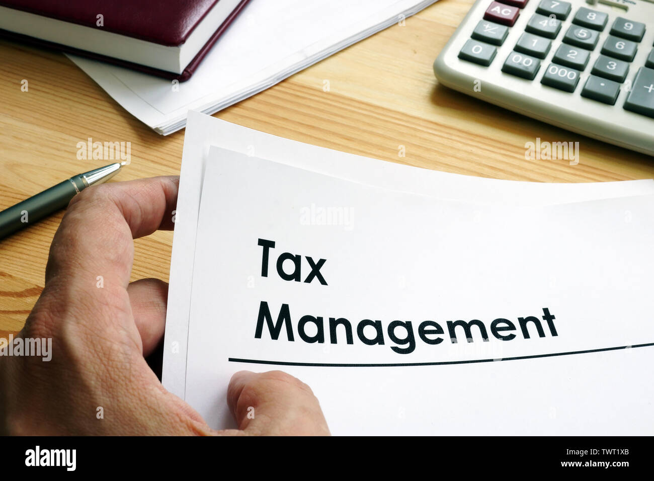 Man is holding Tax Management documents. Stock Photo