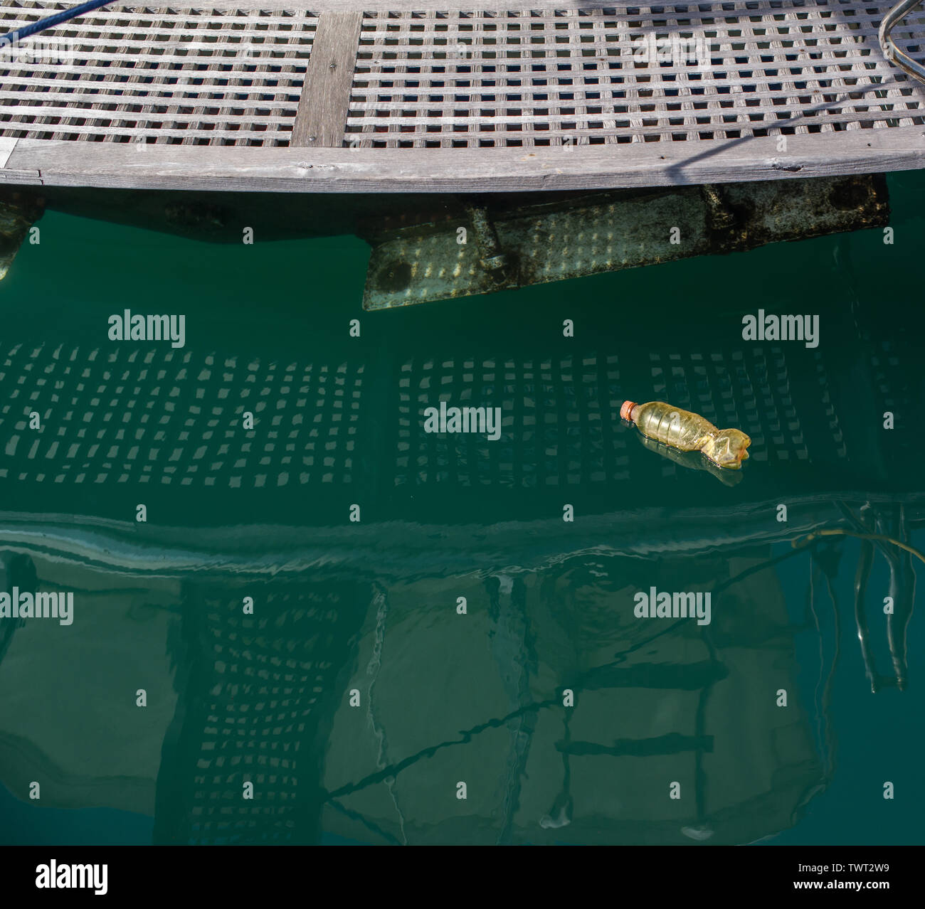 A plastic bottle floats on the surface of the water near the boat berth