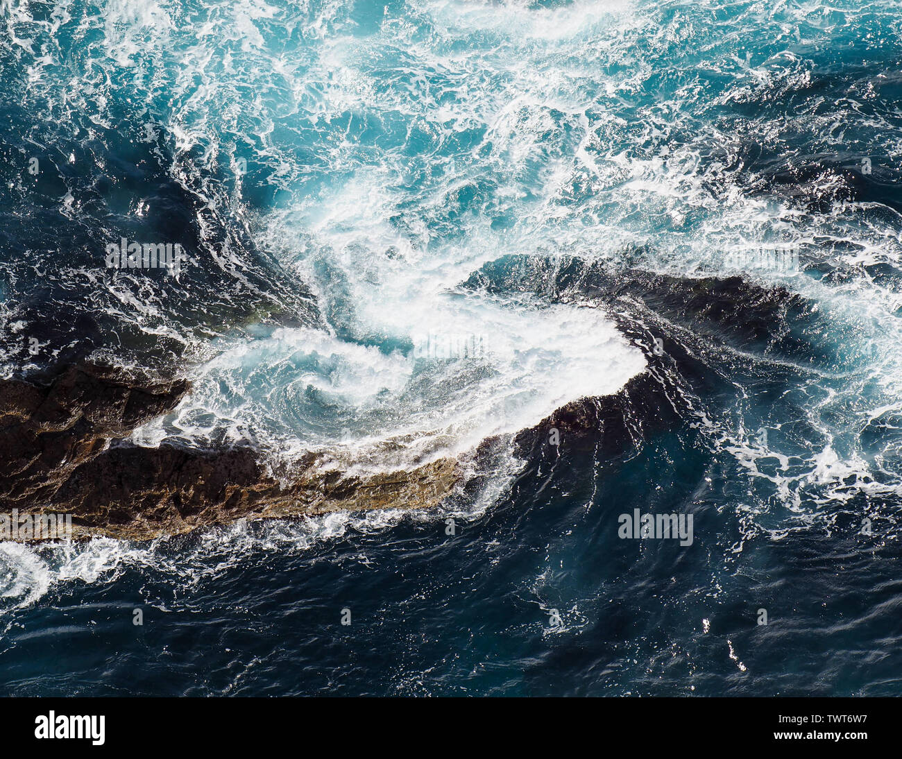 Sea water swirling and churning around rocks, blue and white, Pacific Ocean, Forster NSW, Australia Stock Photo