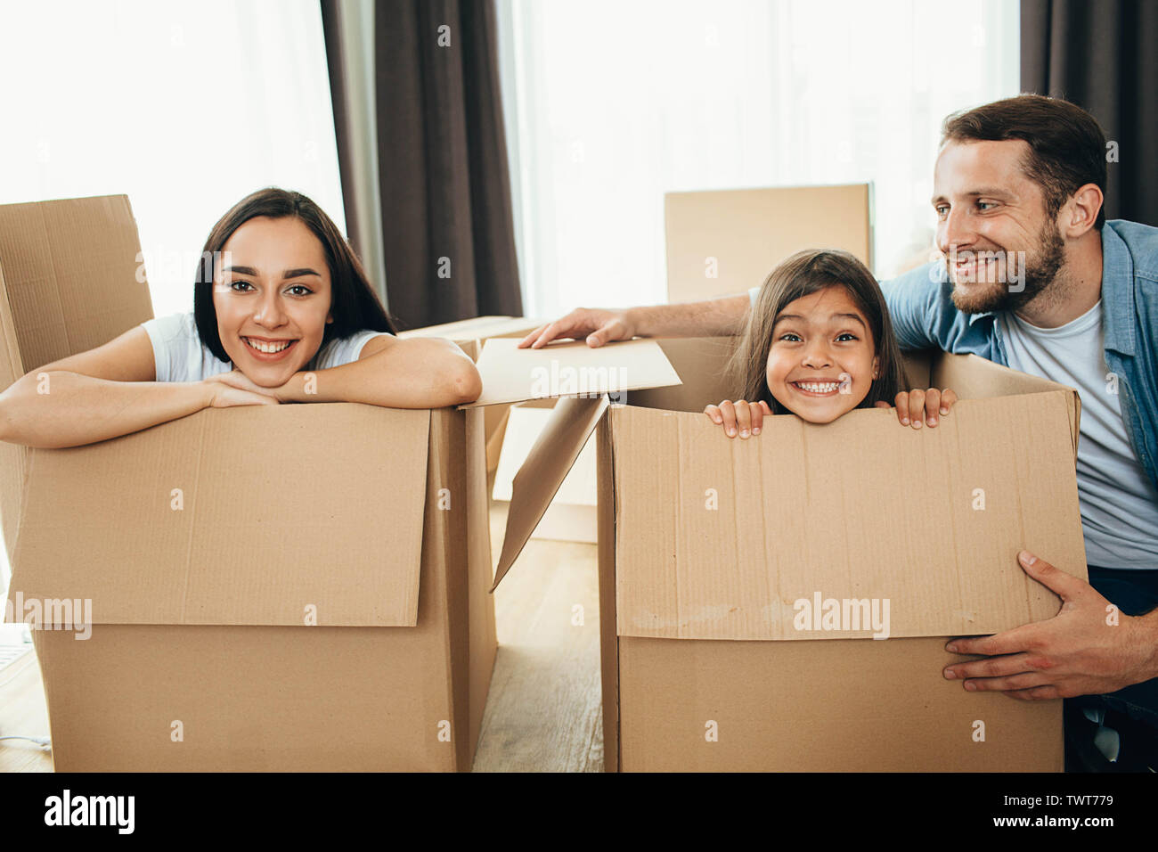 Happy family having fun with Cardboard boxes while moving into new apartment. Mother, father and daughter together smiling, happy young family Stock Photo