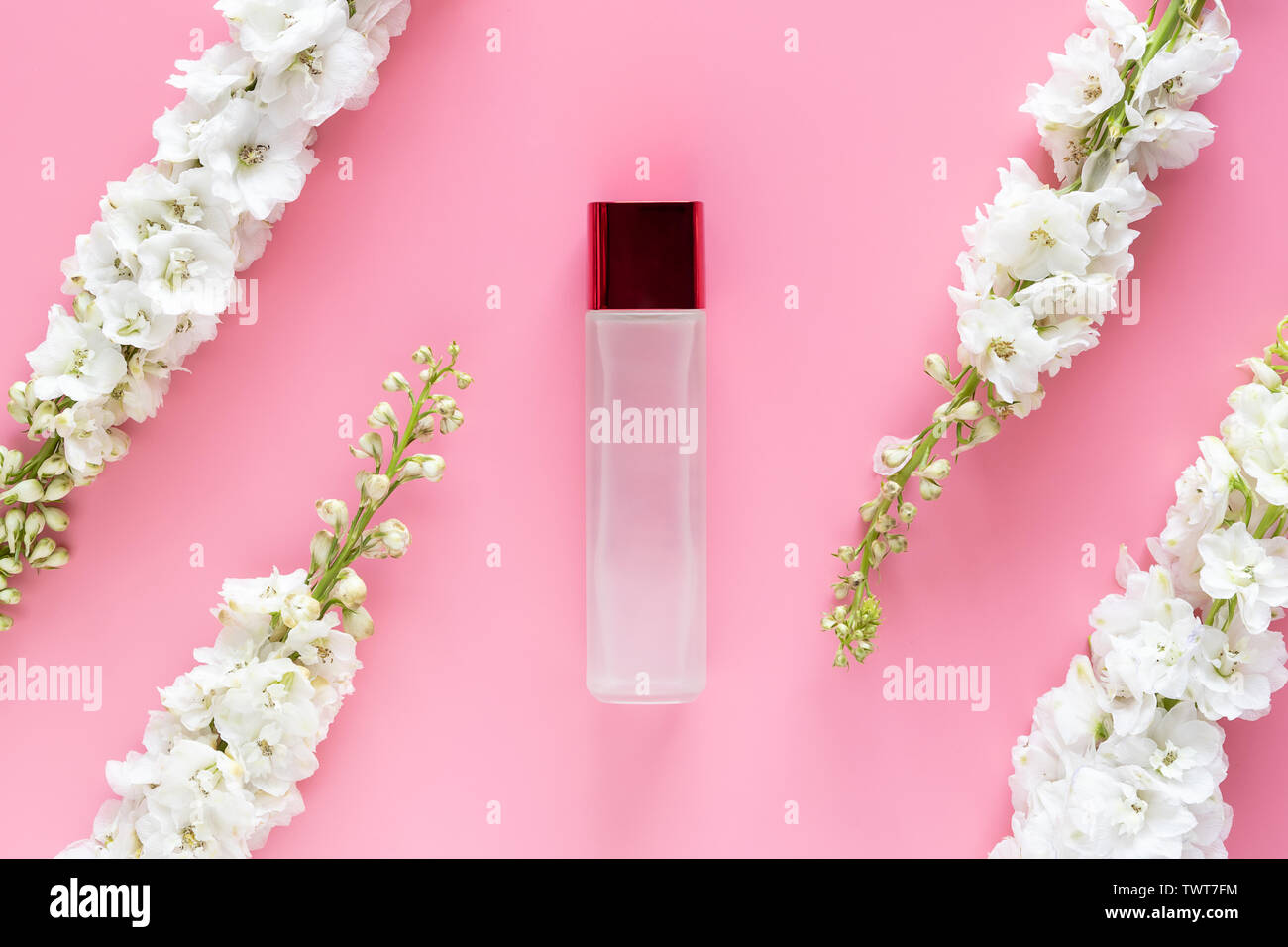 natural beauty skincare product. luxury cosmetic bottle container with white spring flower herbal on pastel pink background. blank label for branding Stock Photo