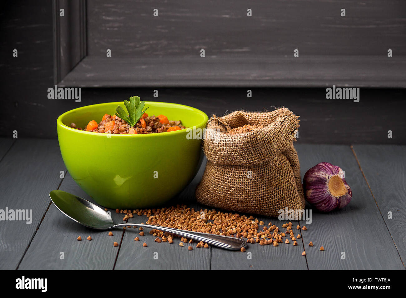 Green bowl of tasty buckwheat porridge on gray wooden table Stock Photo
