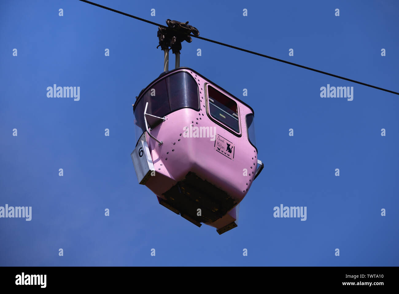 Pink cable car gondola, labeled with 'sweet kitten' and decorated with cats and cat paws. Stock Photo