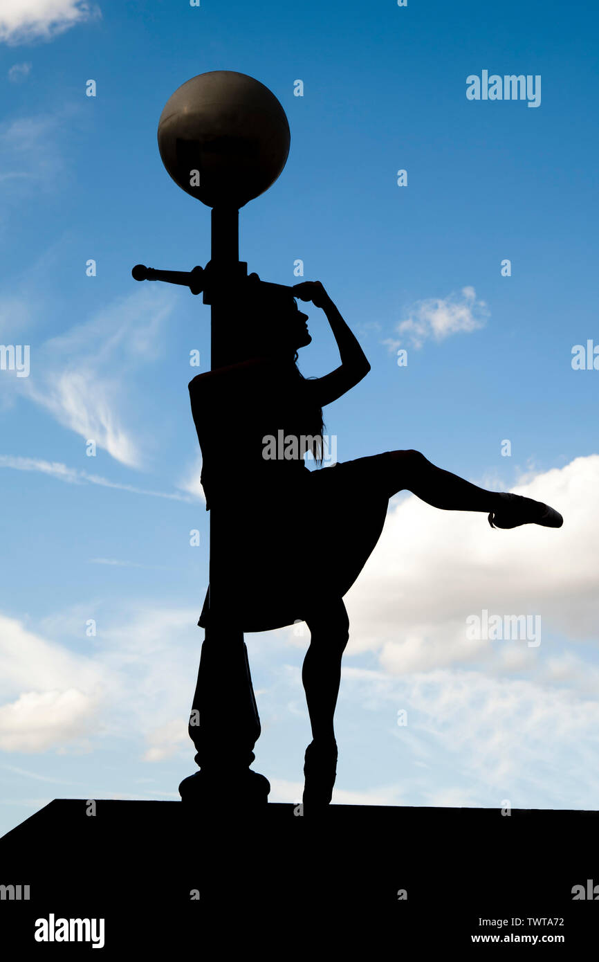 London, England, UK - Silhouette of a ballerina leaning against a lamppost along the river Thames against a blue sky background Stock Photo