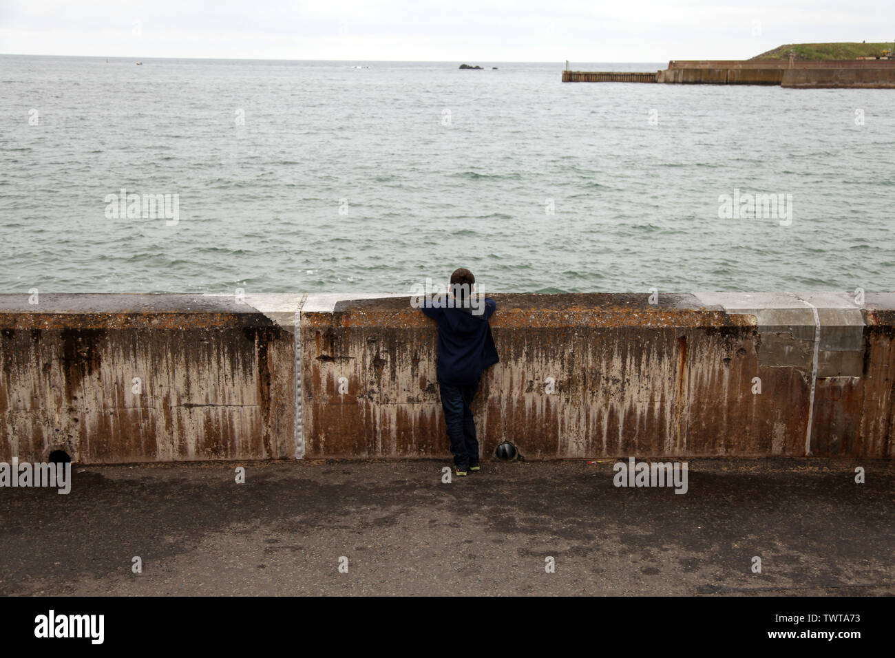 Eyemouth, Scotland, UK - Young boy looking out to sea at the scene of The Eyemouth Fishing Disaster of 1881 or ‘Black Friday’ Stock Photo