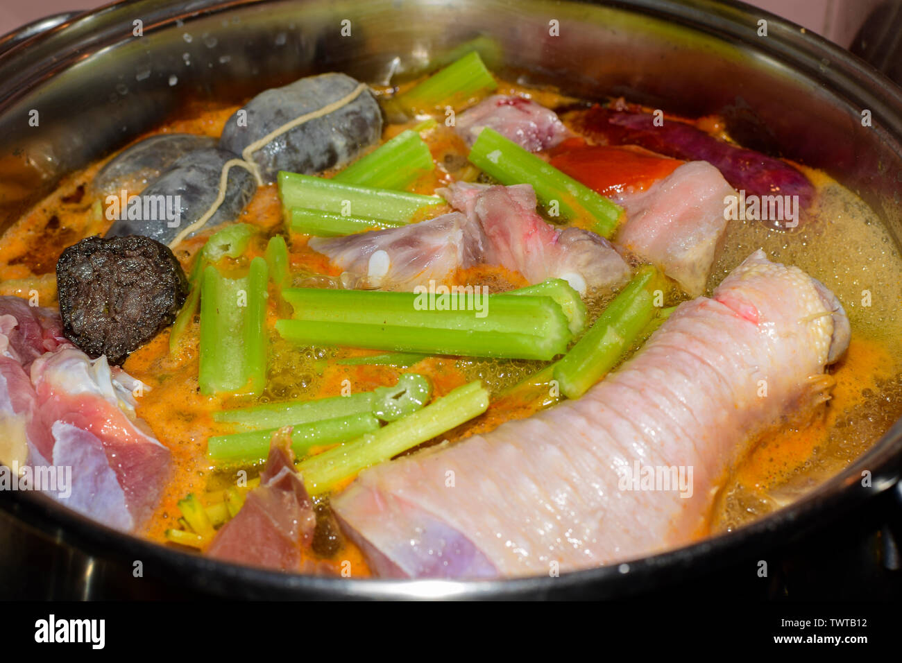 Cooking traditional Spanish pork and chicken stew with blood sausage