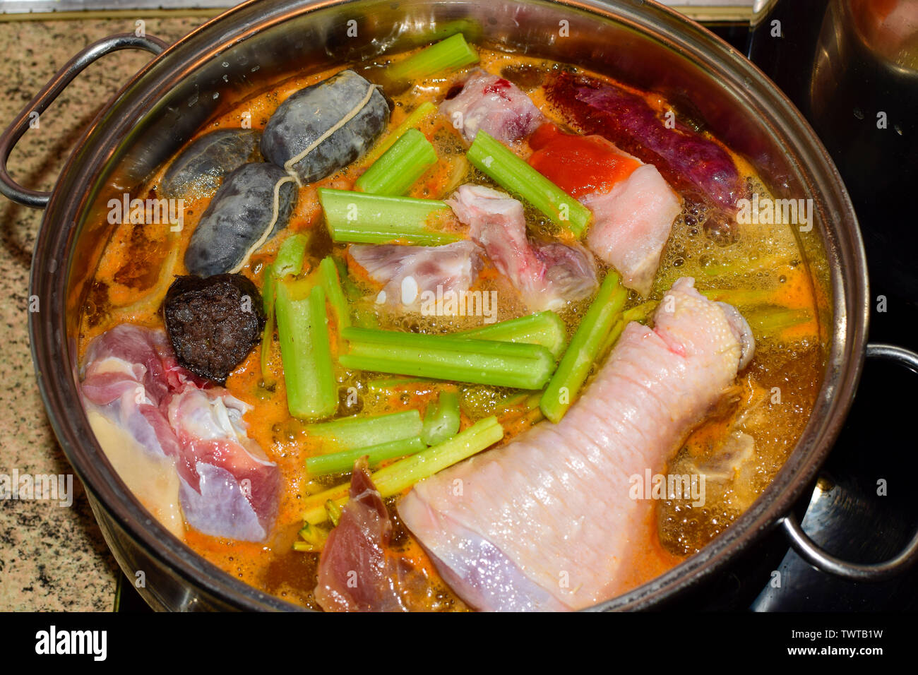 Cooking traditional Spanish pork and chicken stew with blood sausage