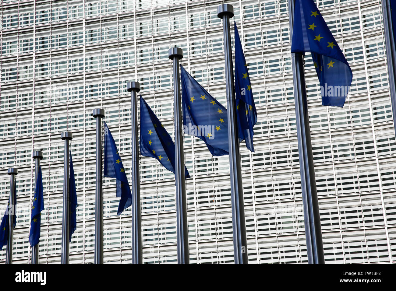 Brussels, Belgium – June 21, 2019: EU flags swing in the air in front of European Commission building Stock Photo
