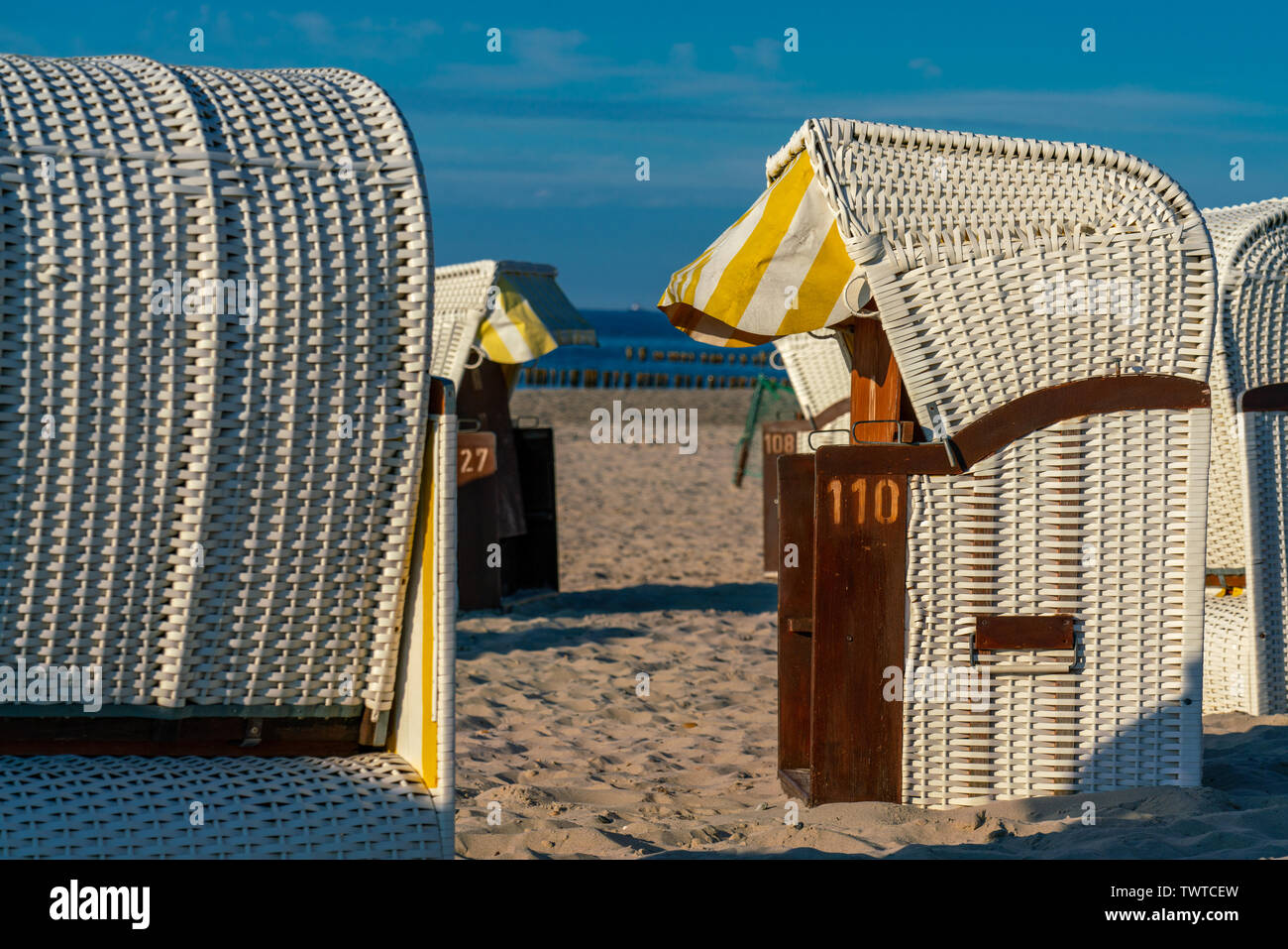 white roofed wicker beach chairs in golden sunlight on a beach in