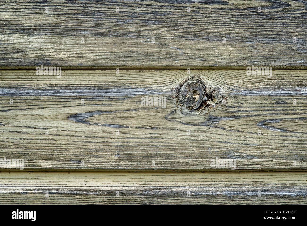 Semi-abstract horizontal, yellow-stained, wooden fence slats with single knot; landscape format. Stock Photo