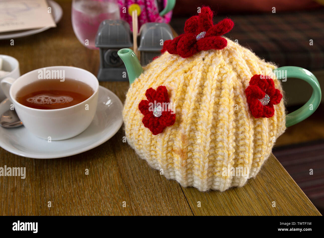 A teapot covered by a colourful wool tea cosy. The tea cosy keeps the tea inside the pot warm