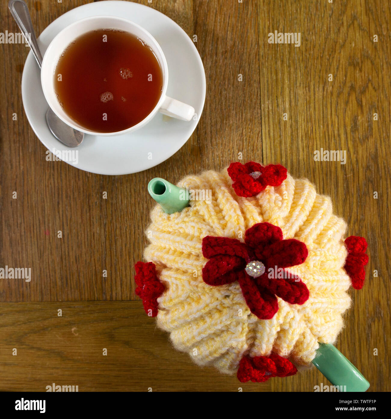 A teapot covered by a colourful wool tea cosy. The tea cosy keeps the tea inside the pot warm