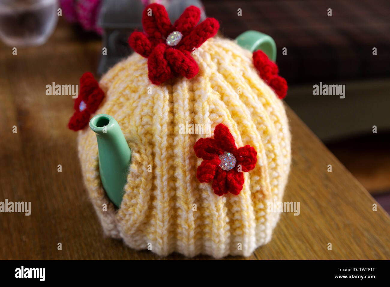 A teapot covered by a colourful wool tea cosy. The tea cosy keeps the tea inside the pot warm