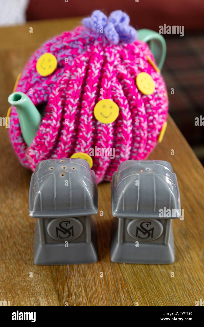 Teapot covered by a  wool tea cosy. It stands next to salt and pepper pots. Stock Photo