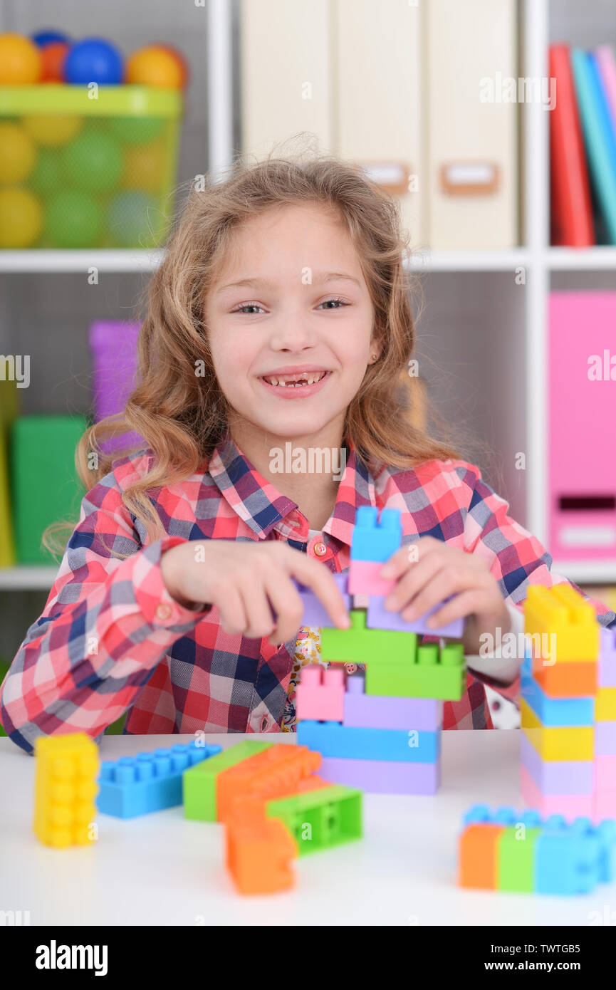 Portrait of little girl playing with colorful plastic blocks at home ...