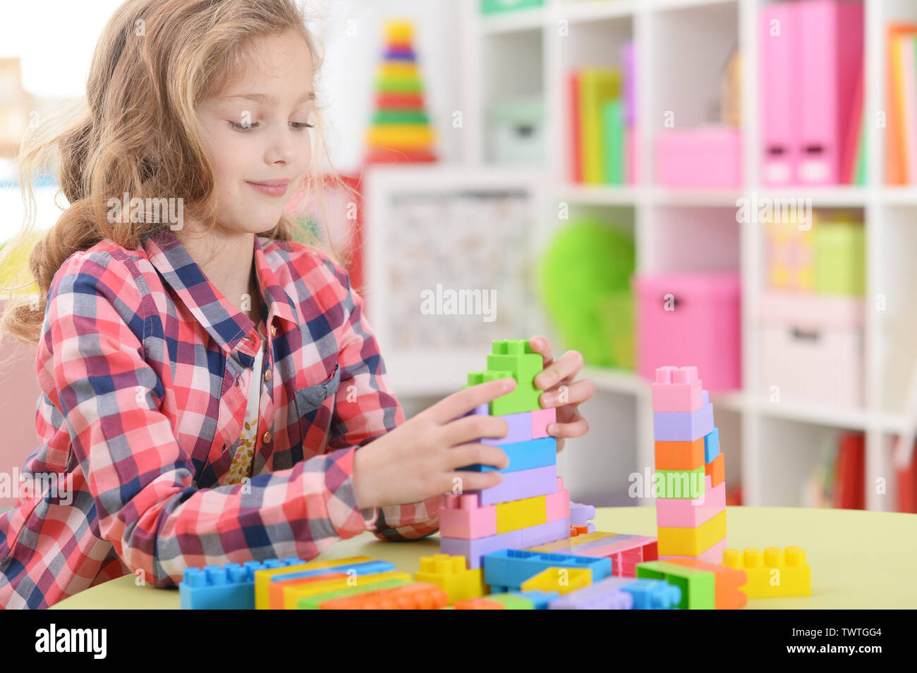 Portrait of little girl playing with colorful plastic blocks at home ...