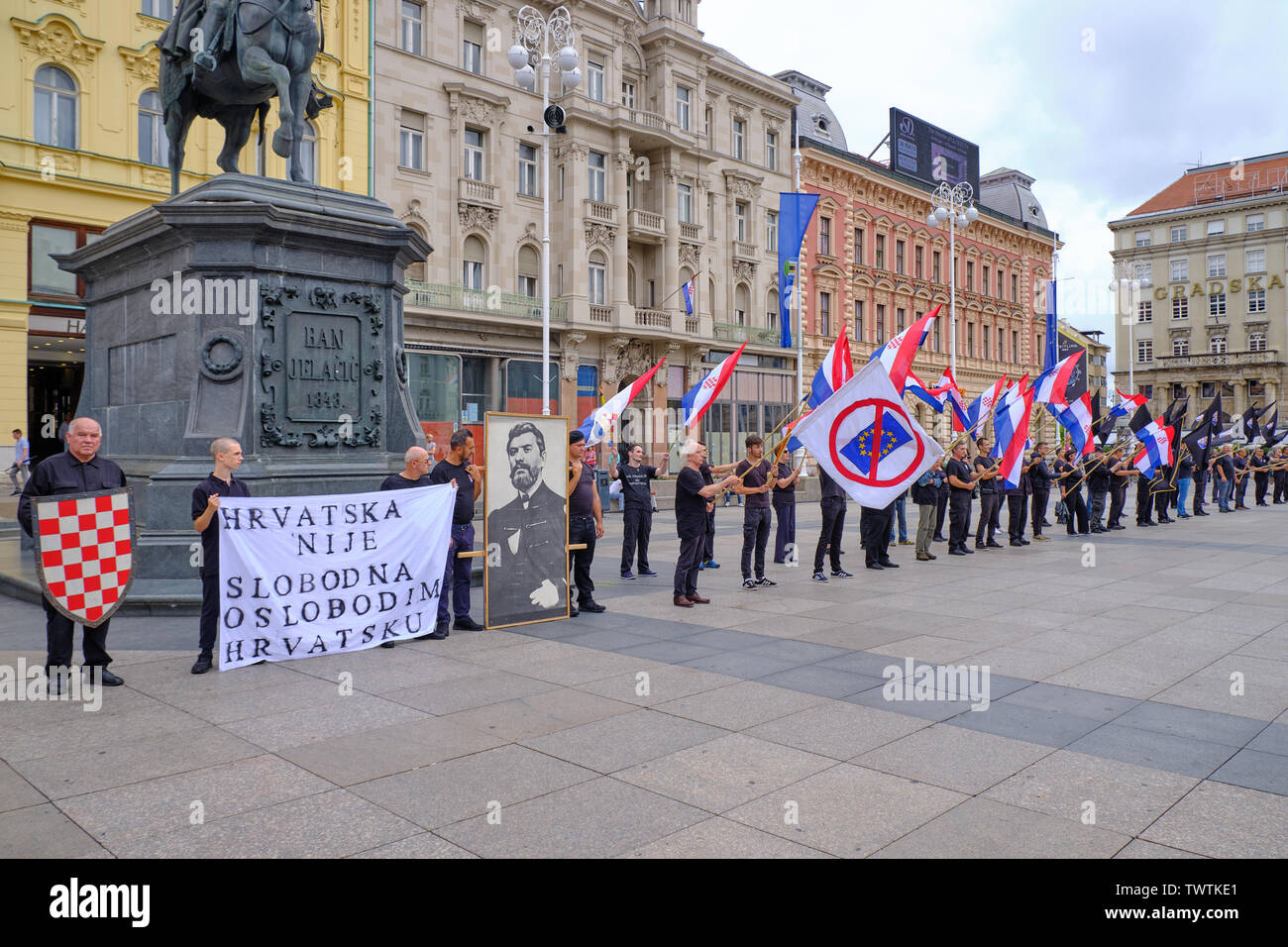 Zagreb, Croatia, June 23, 2019 : HSP lead Right wing political rally , featuring man dressed in black waving Croatian, Black and Anti EU flags Stock Photo