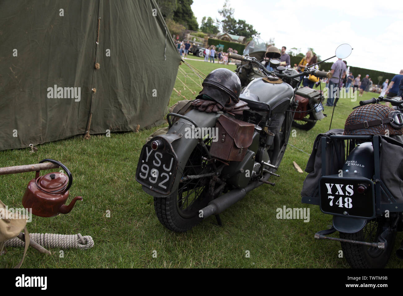 Two military motorbikes parked outside a tent, a blue Royal Enfield motorcycle and a green BSA M20 motorcycle on display at military event Stock Photo