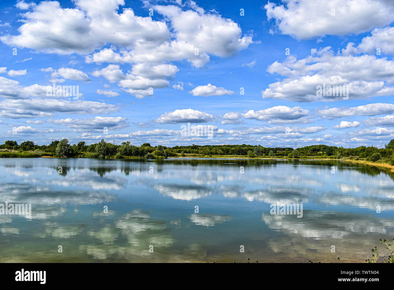 The cloudy sky above is reflected in the still waters of a lake below ...